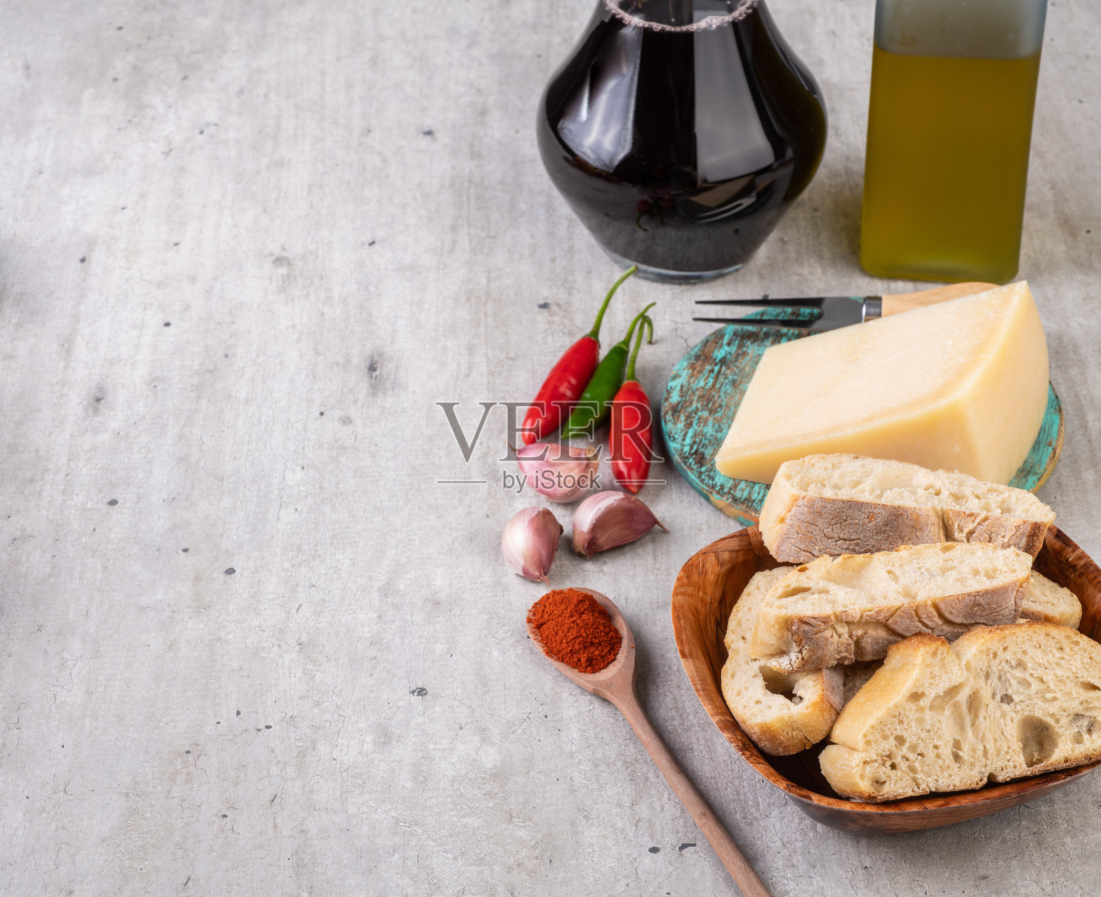 木桌上放着面包、帕尔马干酪、橄榄油、辣椒和大蒜。地中海美食,还有复印空间照片摄影图片