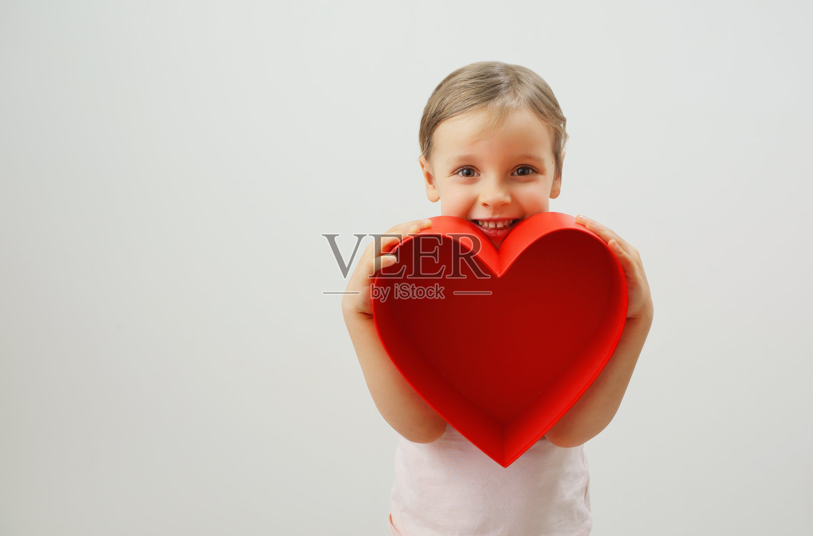 一个快乐的女孩手里拿着一颗大大的红心照片摄影图片