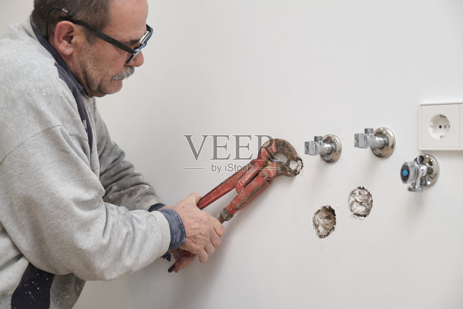 水管工正在用滑套钳拧紧管子上的管件。照片摄影图片