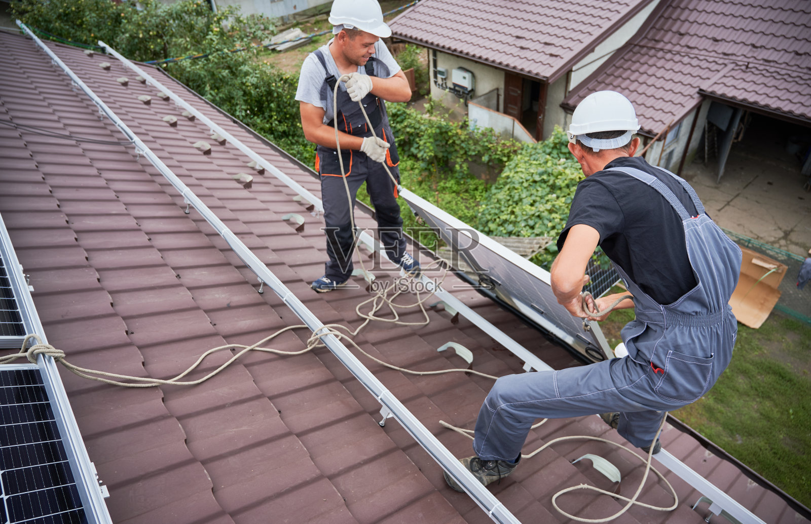 工人在屋顶安装太阳能电池板。照片摄影图片