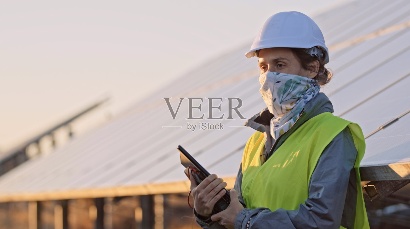 新冠肺炎期间在太阳能发电厂工作的女工程师。可再生能源系统。太阳能城市。照片摄影图片