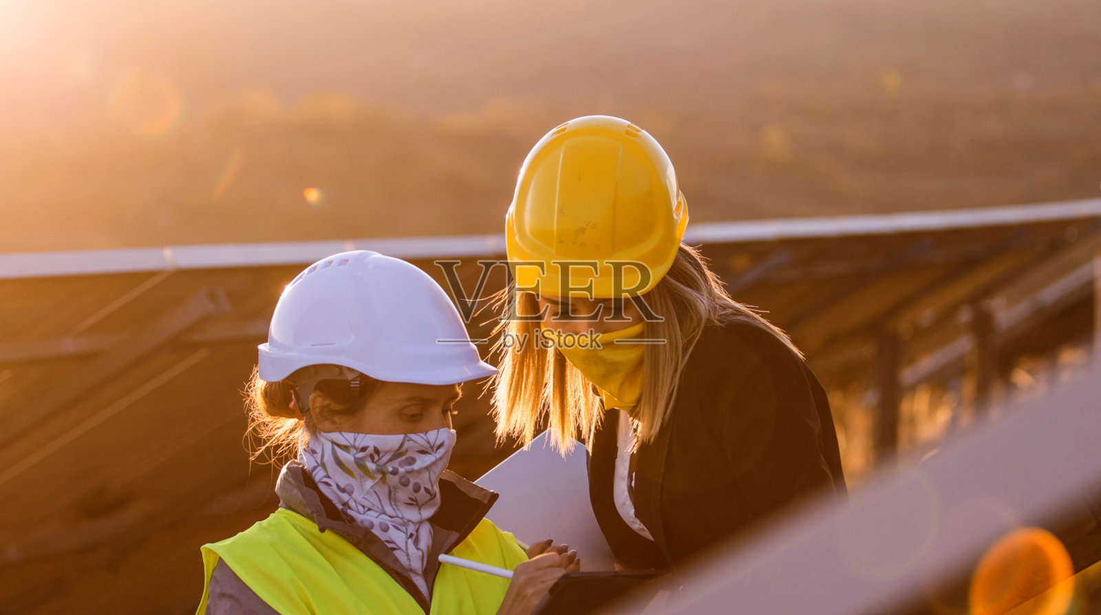 在太阳能发电厂工作的女性工程师。团队合作在COVID-19。可再生能源系统。太阳能城市。照片摄影图片
