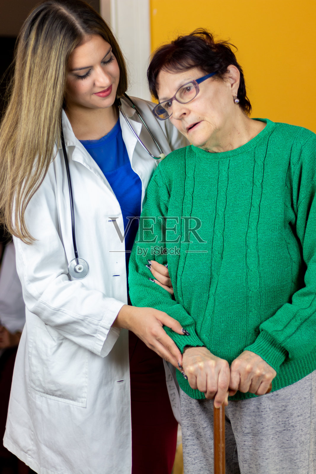 年轻女子的手牵着年老老人的手,带着爱和关怀照片摄影图片