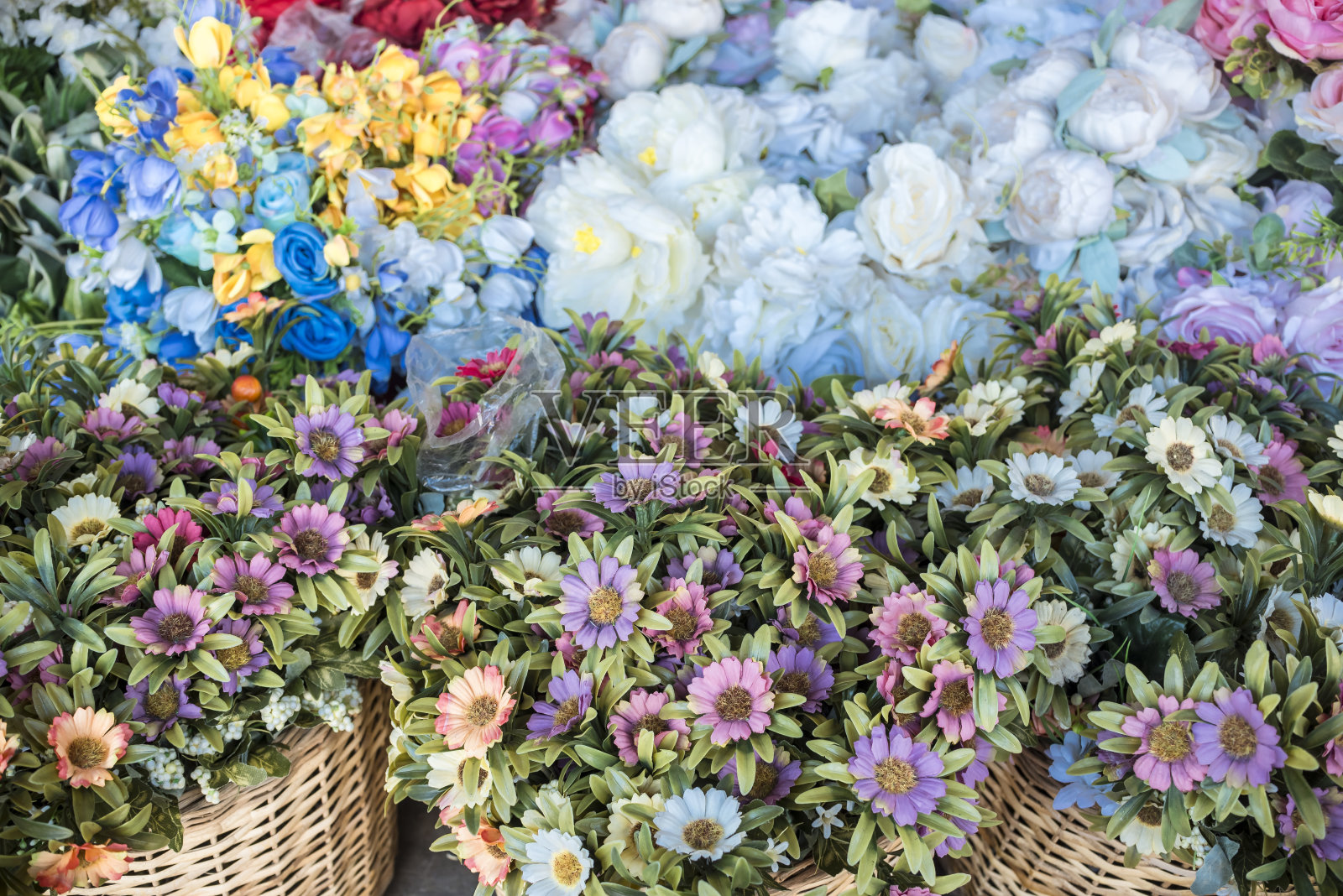 当地市场出售的塑料银莲花和其他人造花。用于装饰目的。照片摄影图片