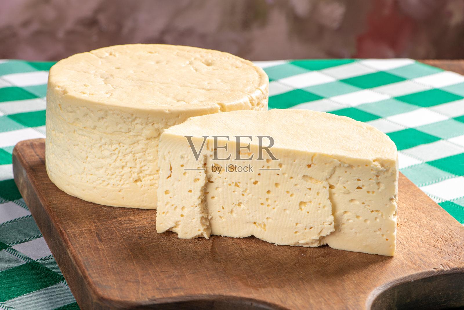 来自巴西的半腌奶酪摆放在一块质朴的木板上,铺着绿白相间的格子桌布。照片摄影图片