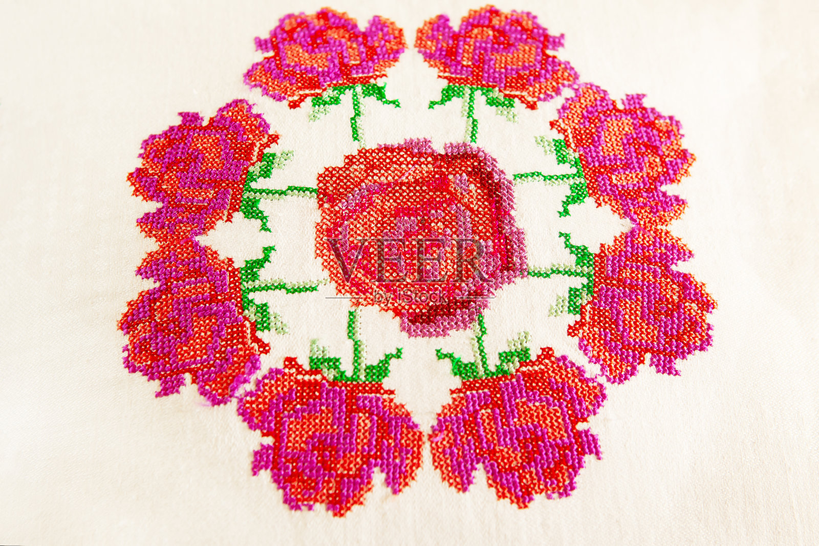 装饰元素,十字绣玫瑰花,在白色亚麻布织物上。绣花机,特写。照片摄影图片