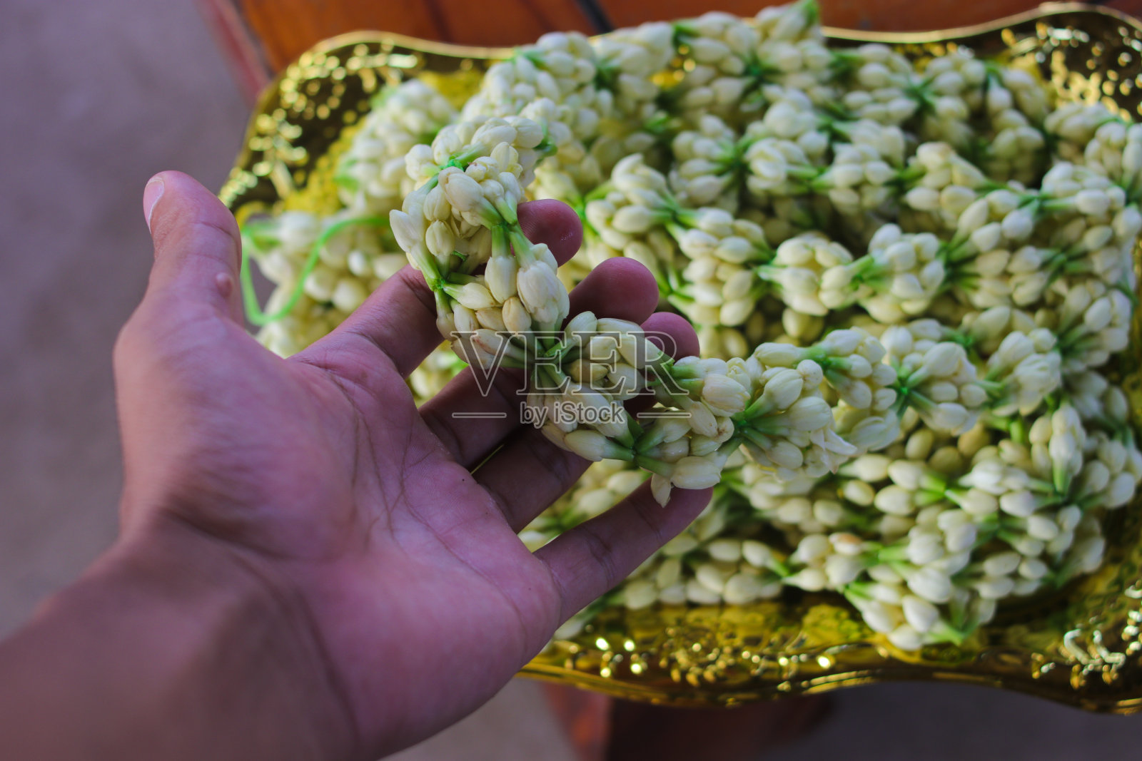 在婚礼传统中,新娘的母亲向新郎佩戴茉莉花项链,象征着对家庭的欢迎照片摄影图片