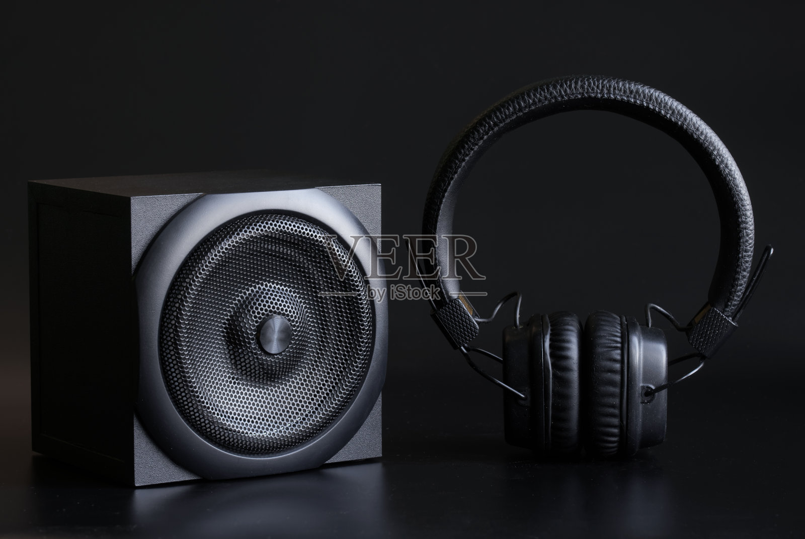 黑色单向扬声器和黑色耳机,耳垫在黑色背景上。现代技术和无线音频的概念照片摄影图片