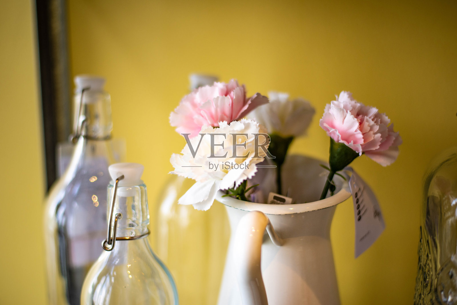 康乃馨花被放置在一个复古风格的水壶里照片摄影图片