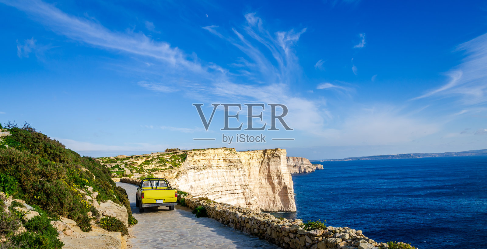 在马耳他戈佐岛萨纳普悬崖附近的一条小路上,一辆黄色的小卡车正在行驶。照片摄影图片