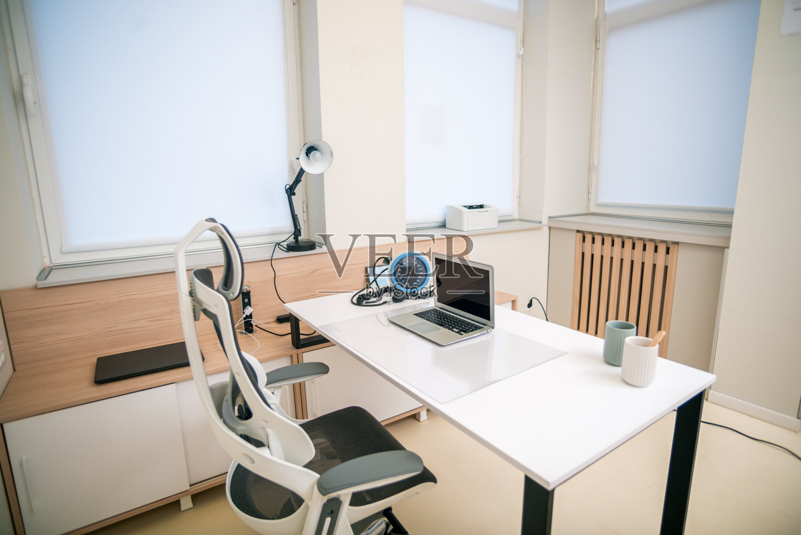 明亮而现代的医生办公室,配有笔记本电脑,台灯和现代椅子。照片摄影图片