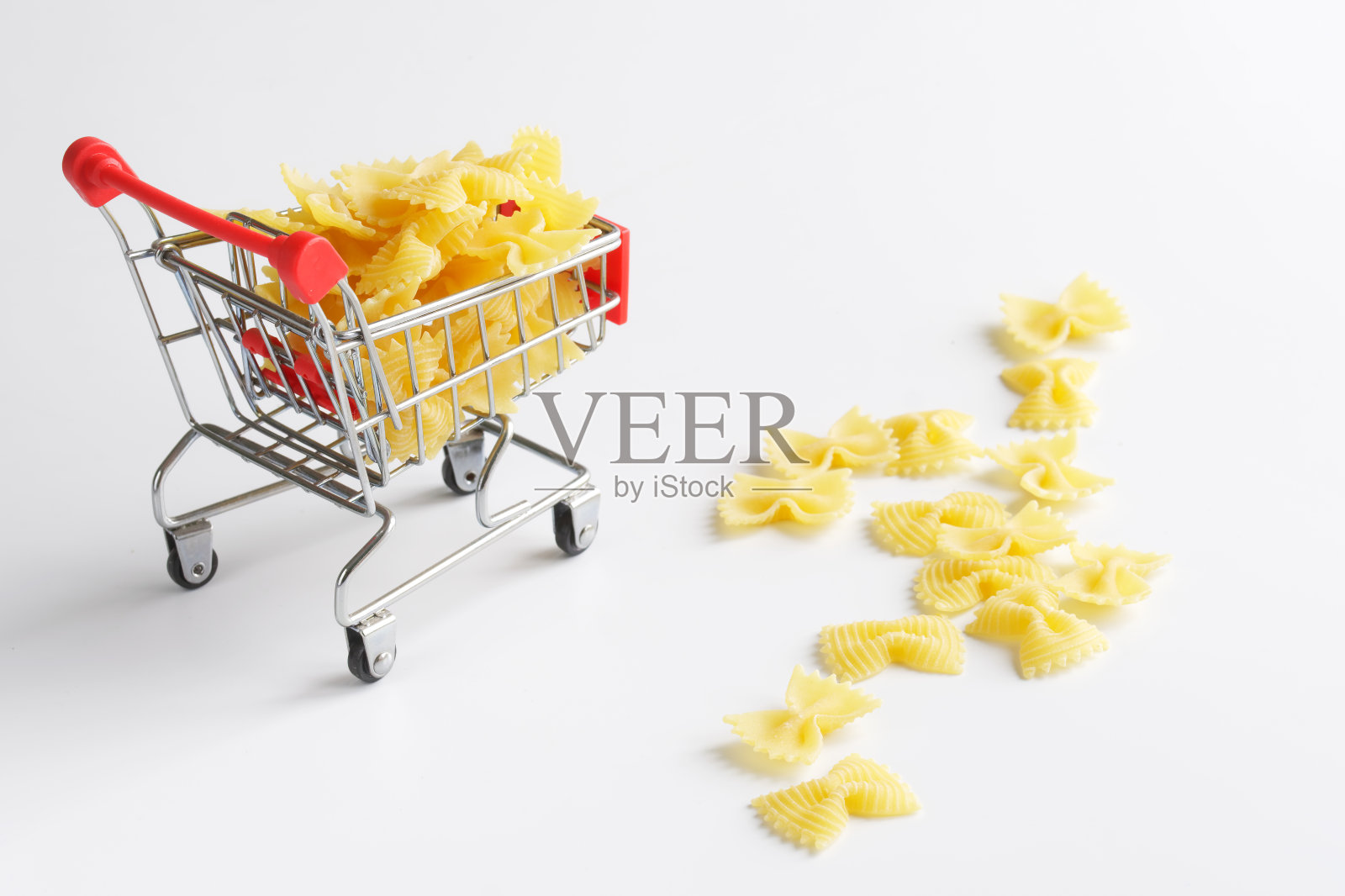 超市手推车里装满了意大利硬面。白色背景。在商店里购买意面和面粉产品的概念照片摄影图片