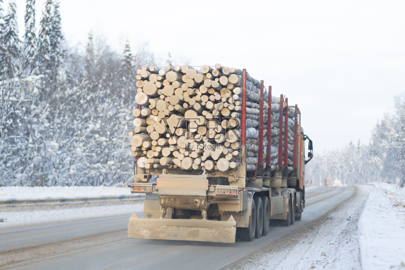 一辆伐木卡车在冬季高速公路上运送木材。照片摄影图片
