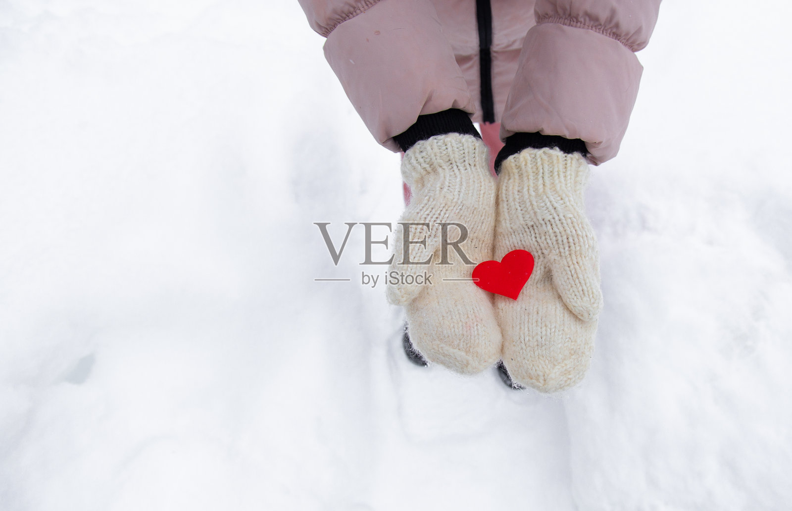 红心躺在新手套上。冬天的雪。这个女人敢在她的手掌里拿出一颗小小的红心。特写镜头。照片摄影图片