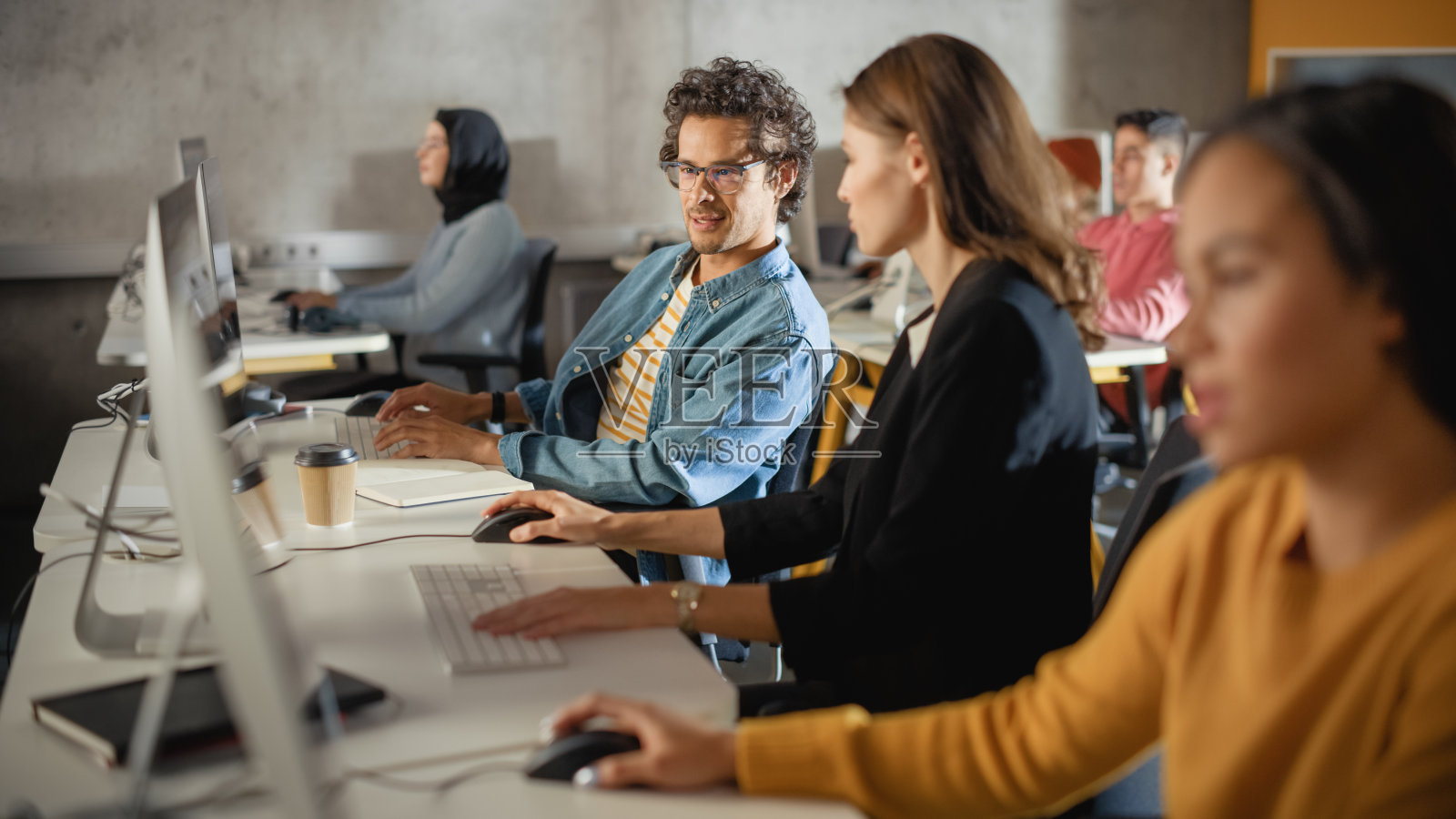聪明的年轻学生在大学与不同种族的同学学习。学者们在大学房间与电脑合作。在课堂上运用知识获取学术技能。照片摄影图片