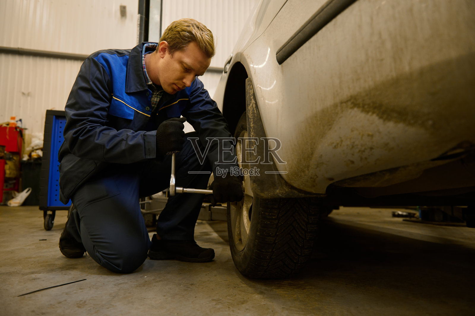 年轻的白人汽车修理工在汽车修理厂检查车轮。汽车行业机械维修工程师。汽车维修服务理念照片摄影图片