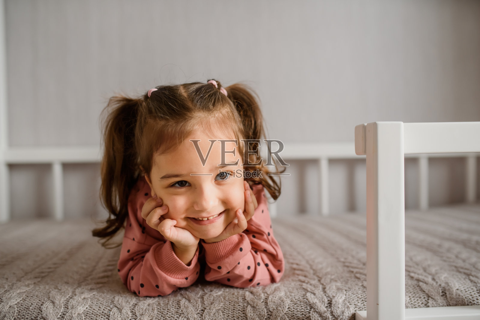 小女孩正躺在床上微笑。照片摄影图片