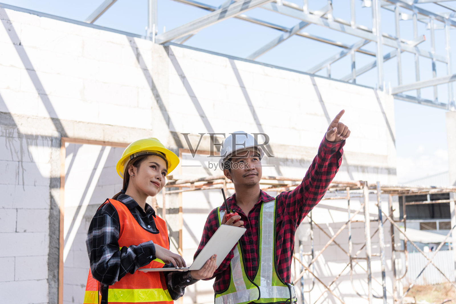 亚洲工程师,领班,工人,男女在建筑工地使用笔记本电脑和无线电交谈照片摄影图片