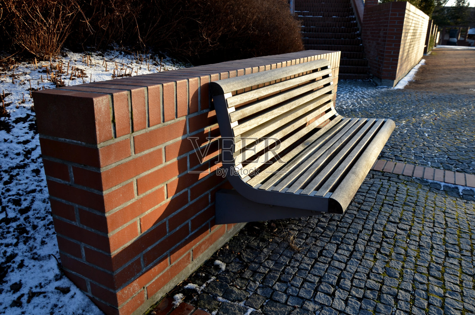 楼梯和栏杆的外露砖光滑表面。u形砖挡土墙角落的金属栏杆和长凳。凹进去的灯照亮了行人的脚底照片摄影图片