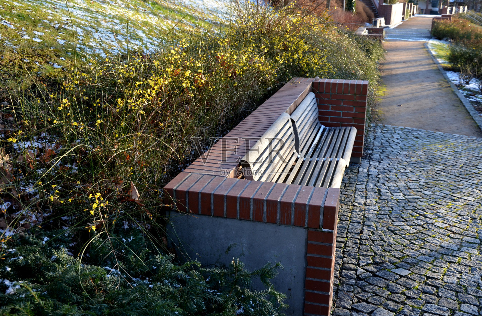 楼梯和栏杆的外露砖光滑表面。u形砖挡土墙角落的金属栏杆和长凳。凹进去的灯照亮了行人的脚底照片摄影图片