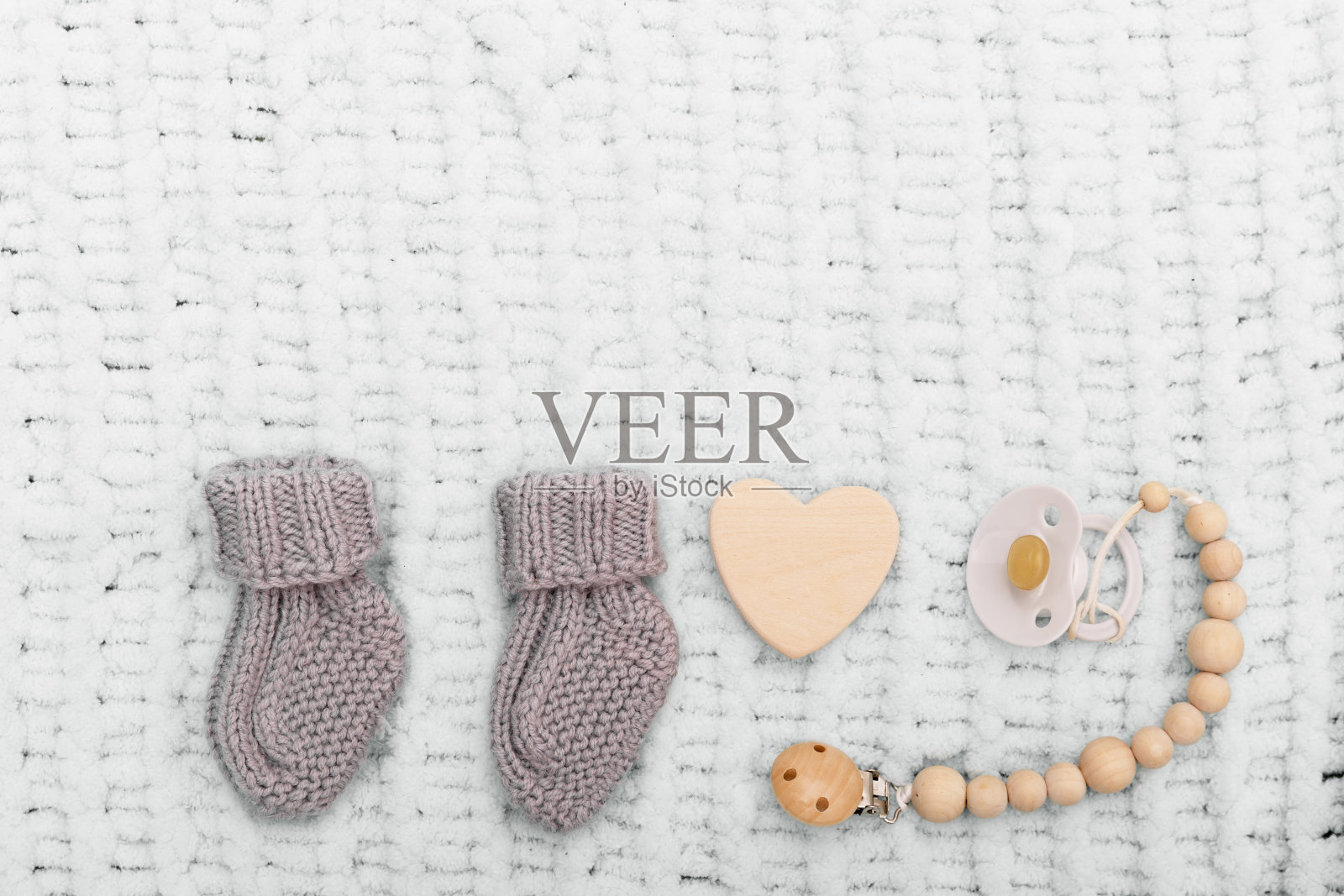 灰色的针织婴儿袜,一个奶嘴和蓝色柔软毯子上的心形图案。孩子期望的概念。新生儿的可爱东西。复制空间,平铺,俯视图。照片摄影图片