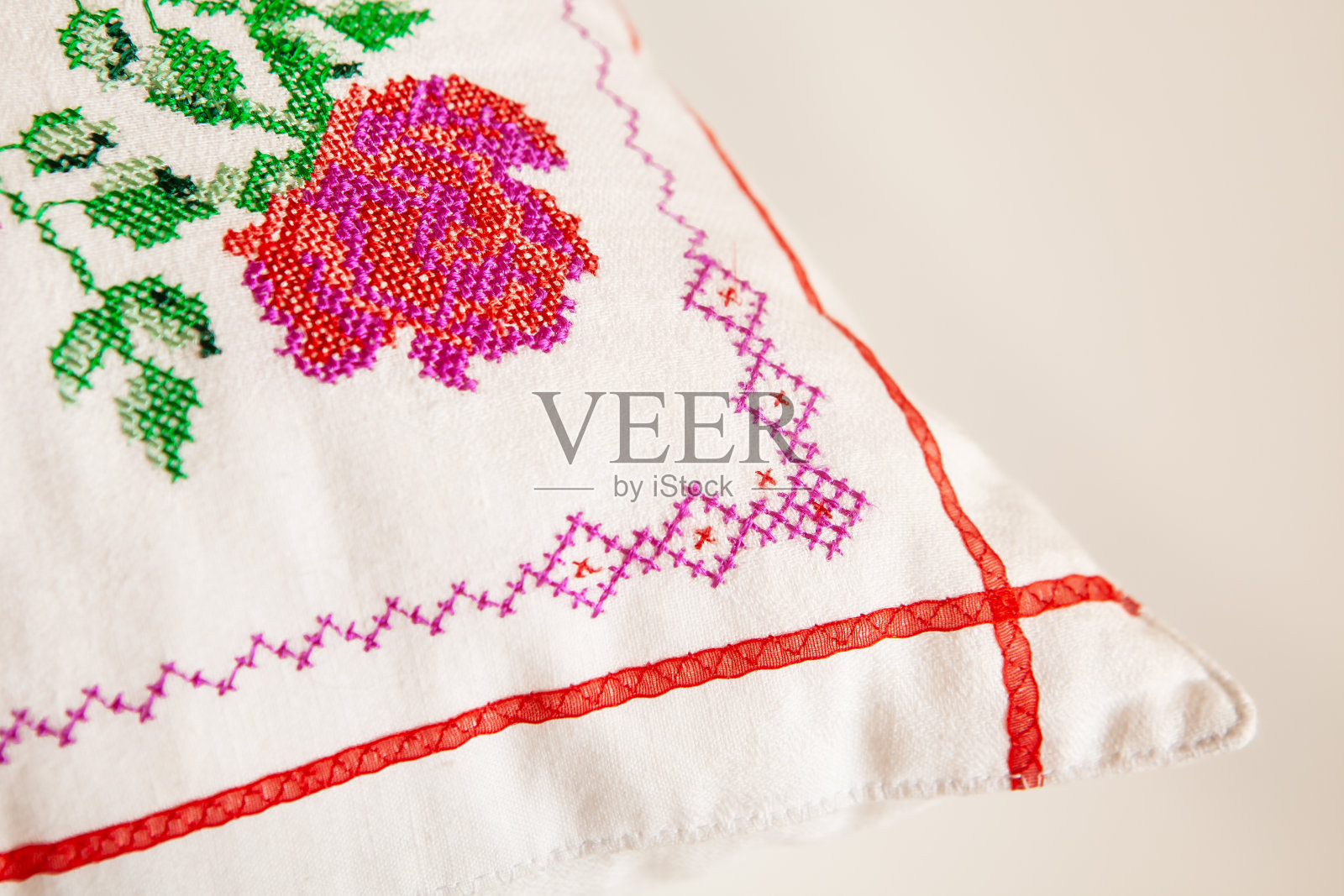 装饰元素,十字绣玫瑰花,在白色亚麻布织物上。绣花机,特写。照片摄影图片