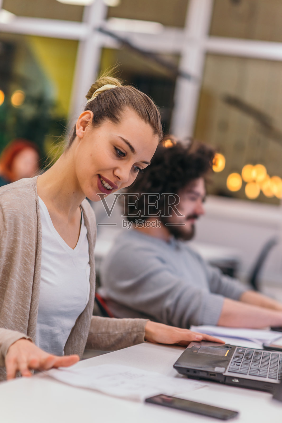 两个同事在现代初创公司的办公室里做一个项目。一个留着非洲式发型的男人和一个在办公室工作的金发女员工。照片摄影图片