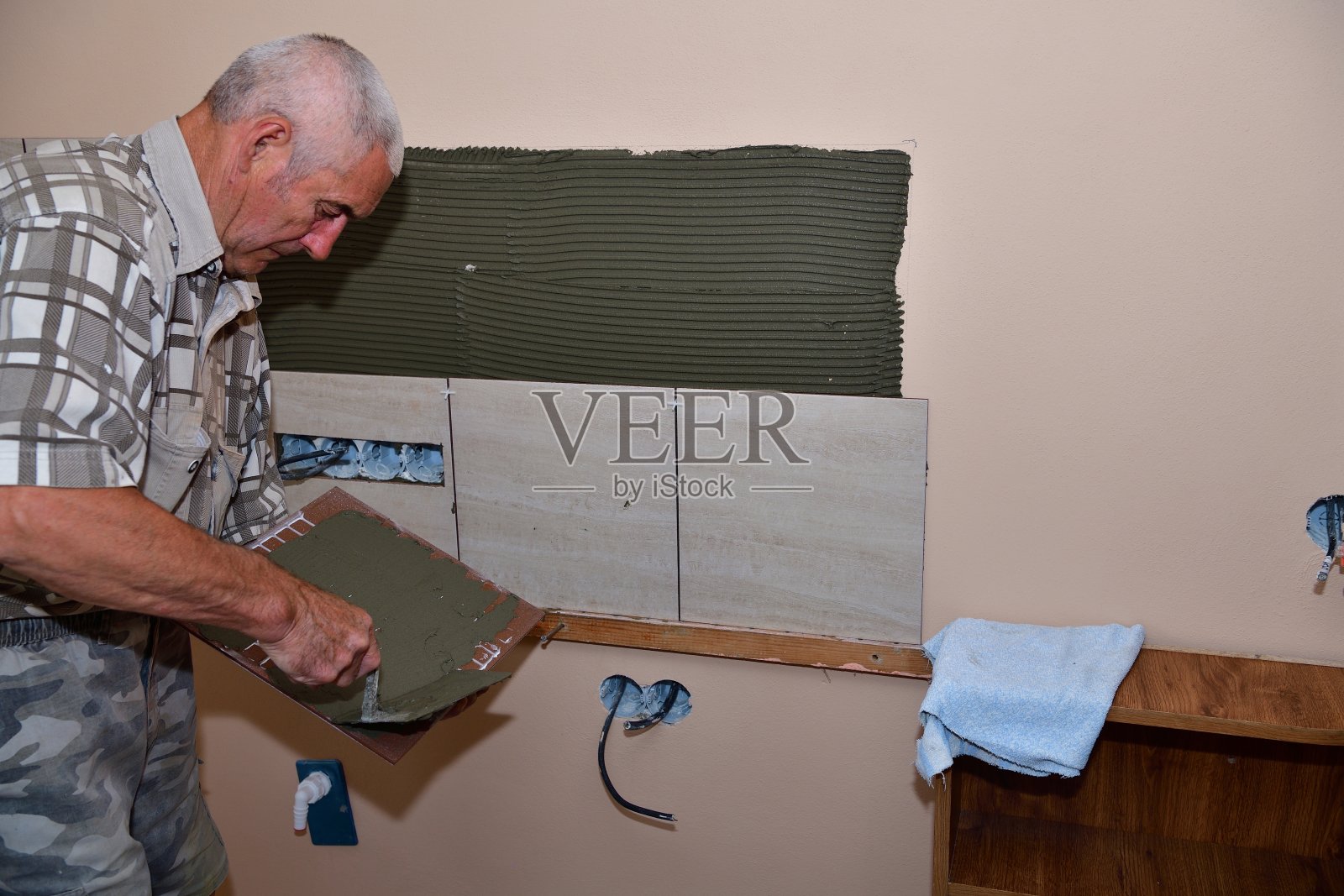 泥瓦匠在厨房的墙上贴瓷砖照片摄影图片