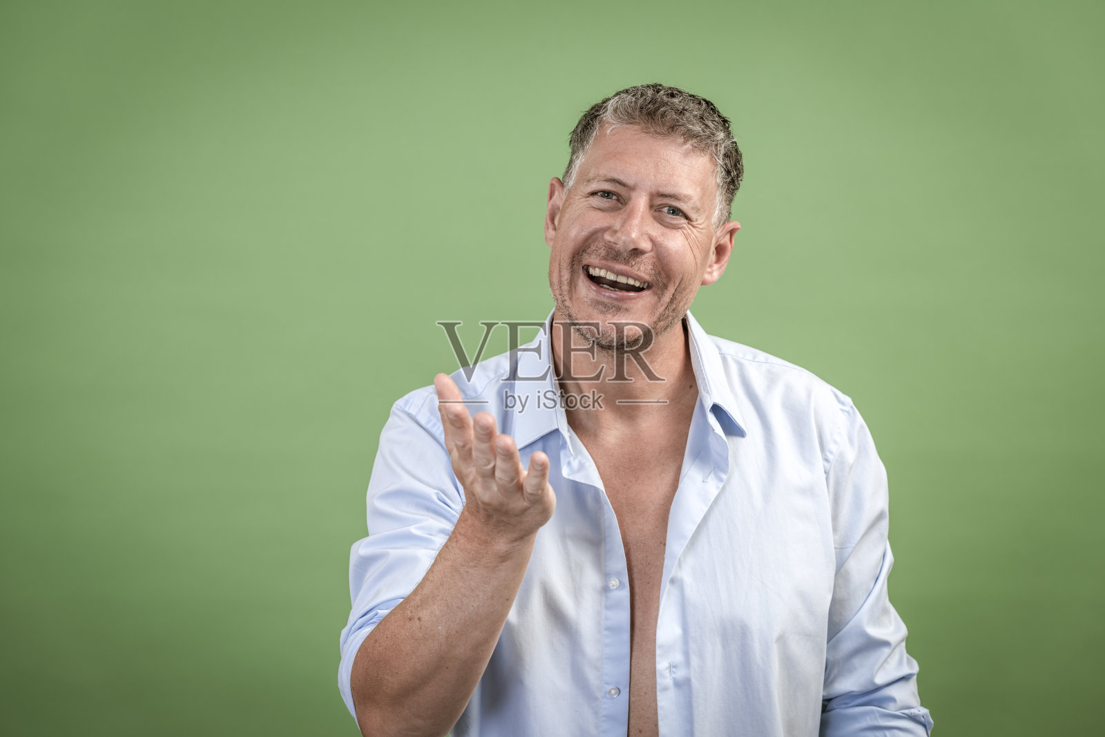 一个穿着敞开的蓝色衬衫的人站在绿色的墙前照片摄影图片