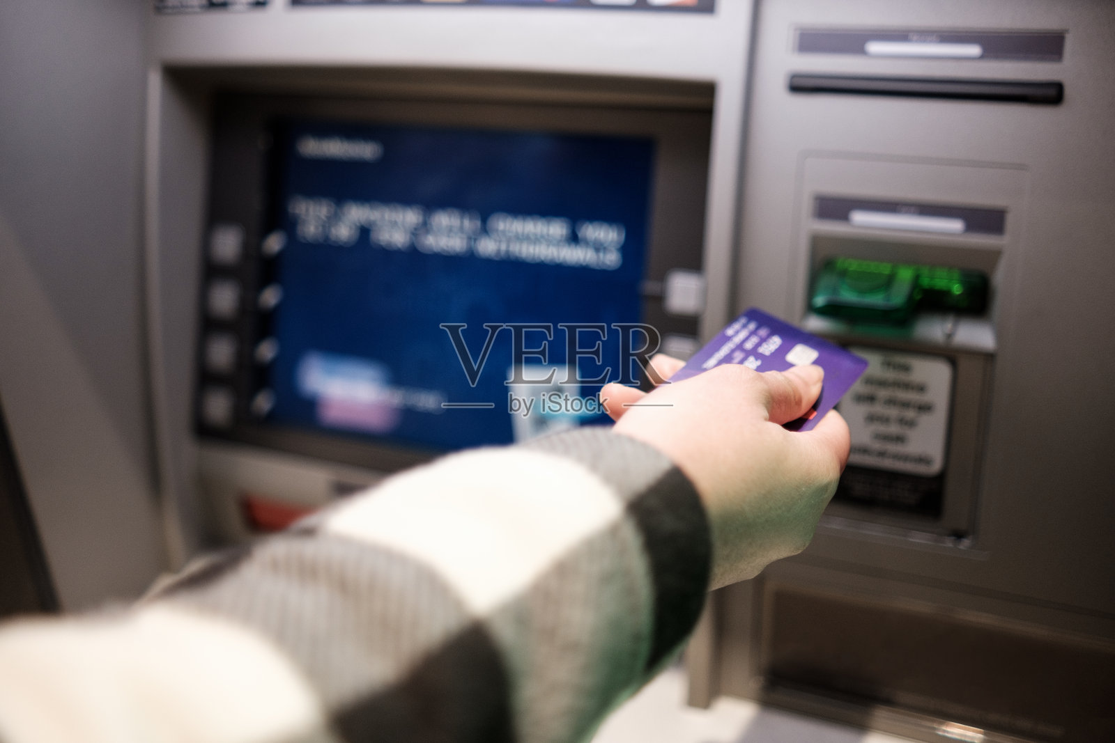 女性手插入信用卡在取款机。照片摄影图片