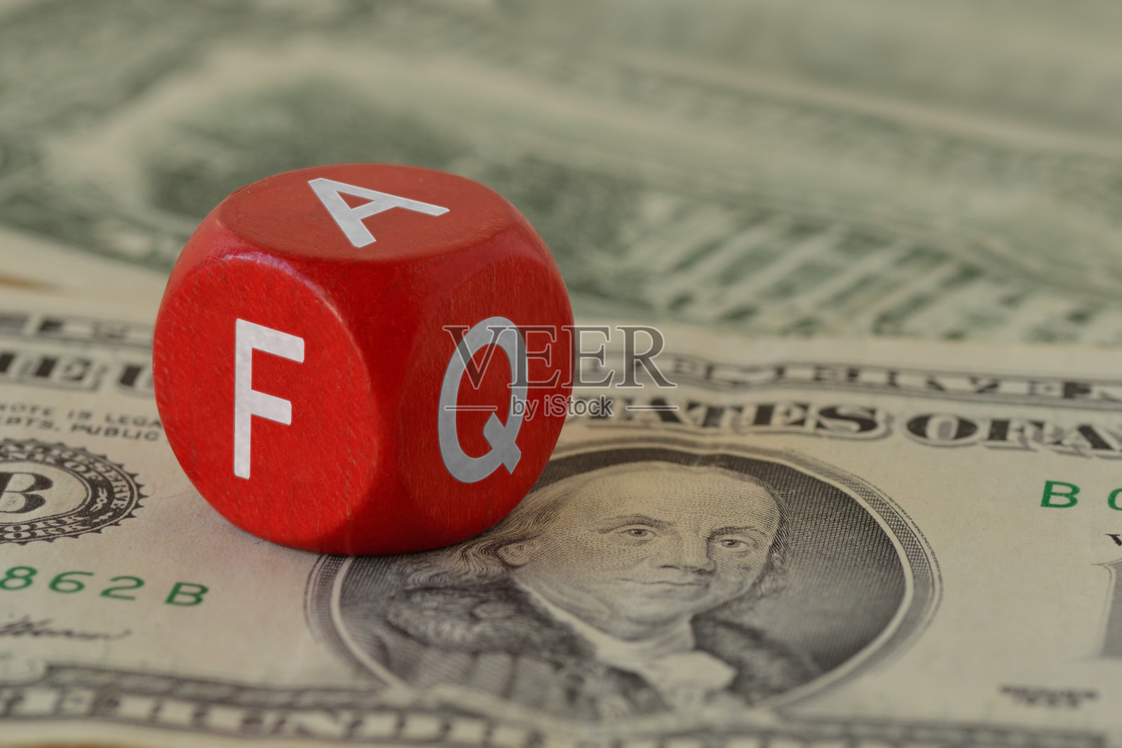 木制骰子与字常见问题对美元钞票的背景-经济概念和经常问的问题照片摄影图片