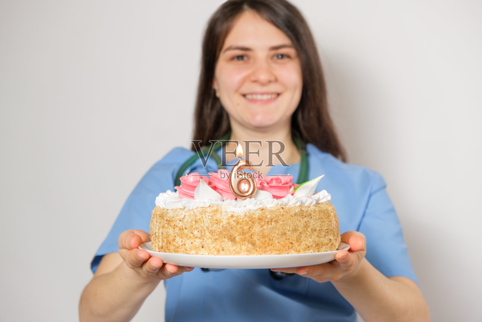 医生或护士拿着一个数字6的生日蛋糕庆祝诊所开业周年照片摄影图片