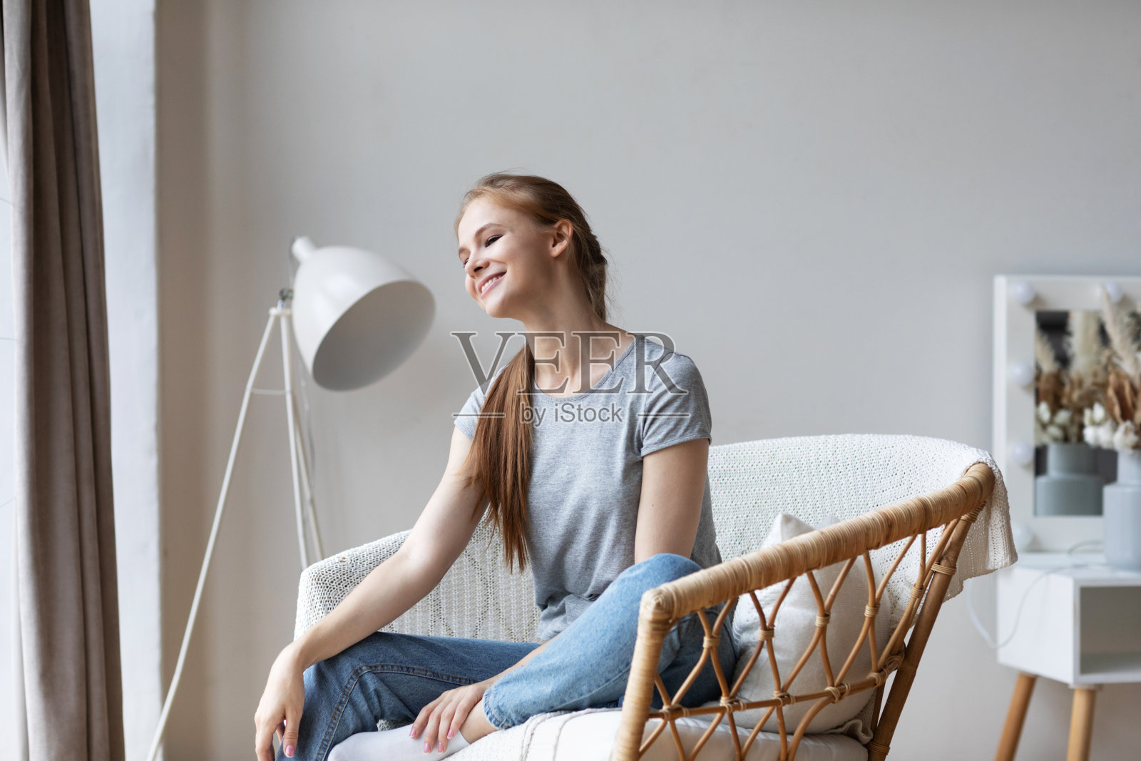 可爱的冷静微笑的女孩的肖像在舒适的扶手椅在家里。放松在家里照片摄影图片
