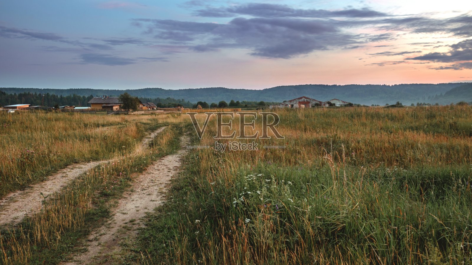 乡村的土路穿过地平线上的山丘。照片摄影图片