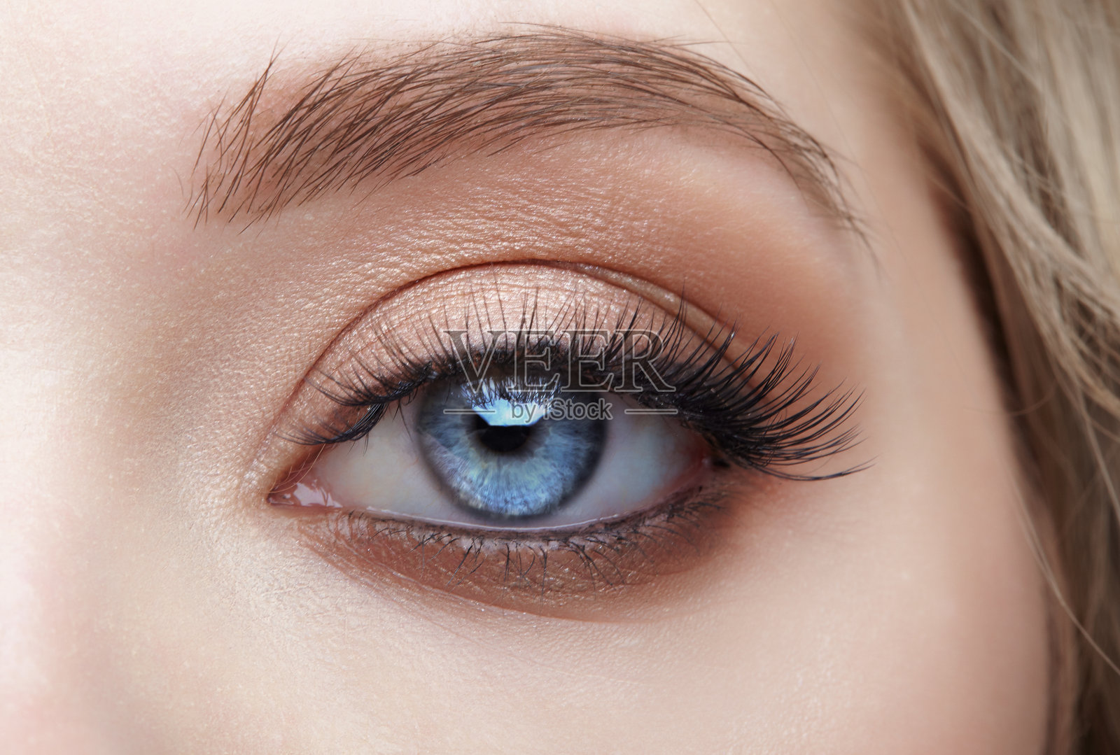 特写微距镜头的蓝色人类女性眼睛。女人用自然美丽的妆容。照片摄影图片