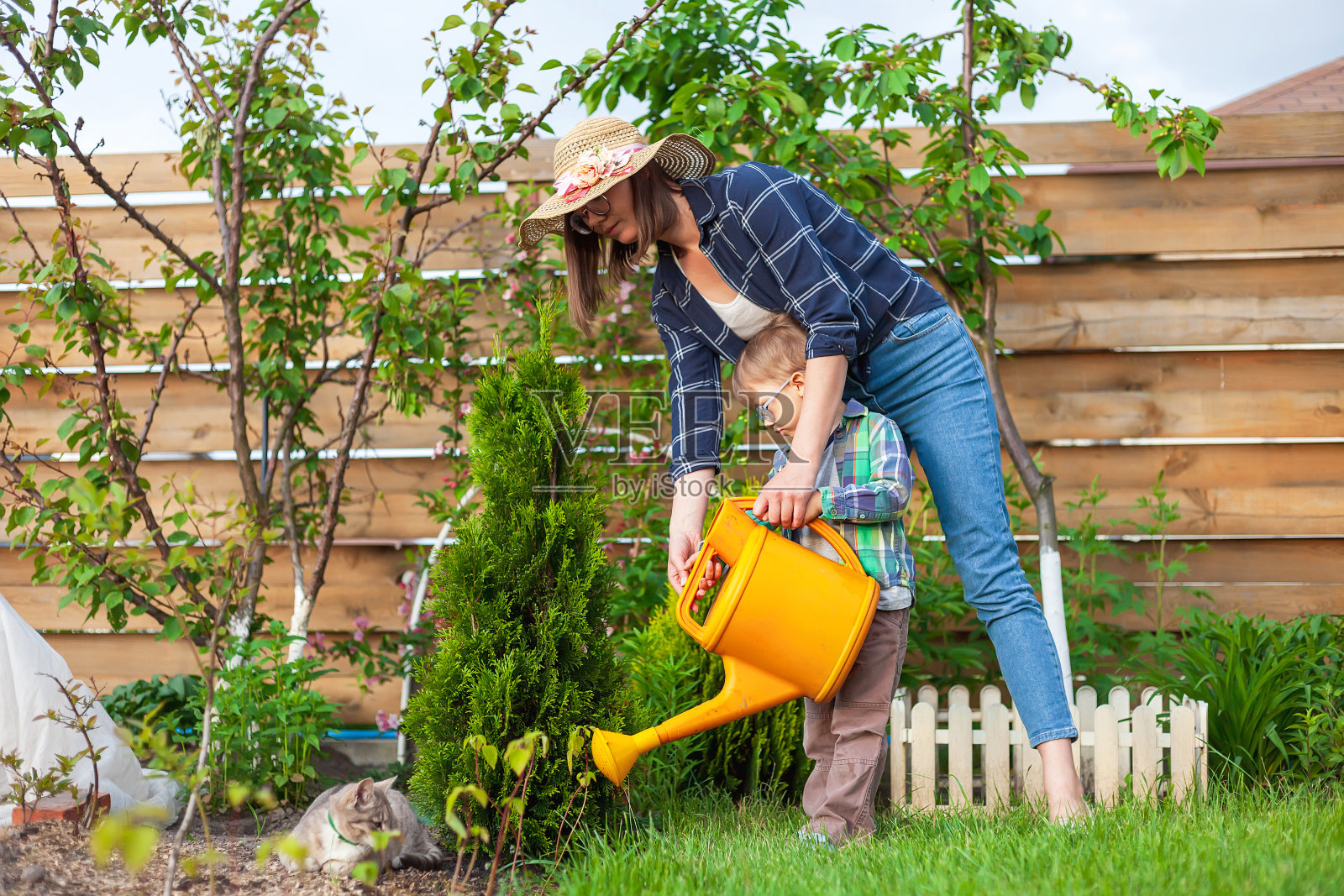 孩子和母亲可以在后院给花园浇水照片摄影图片
