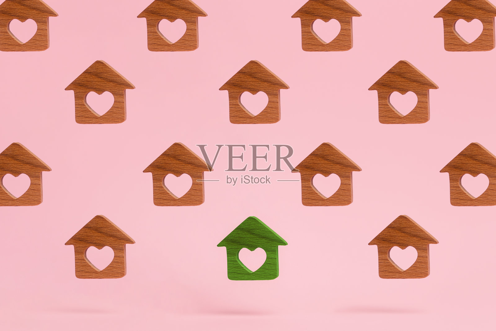 抽象的小木屋,里面雕刻着一颗心。绿色家园在中间。粉红色的背景。抵押、房屋购置和租赁的概念照片摄影图片