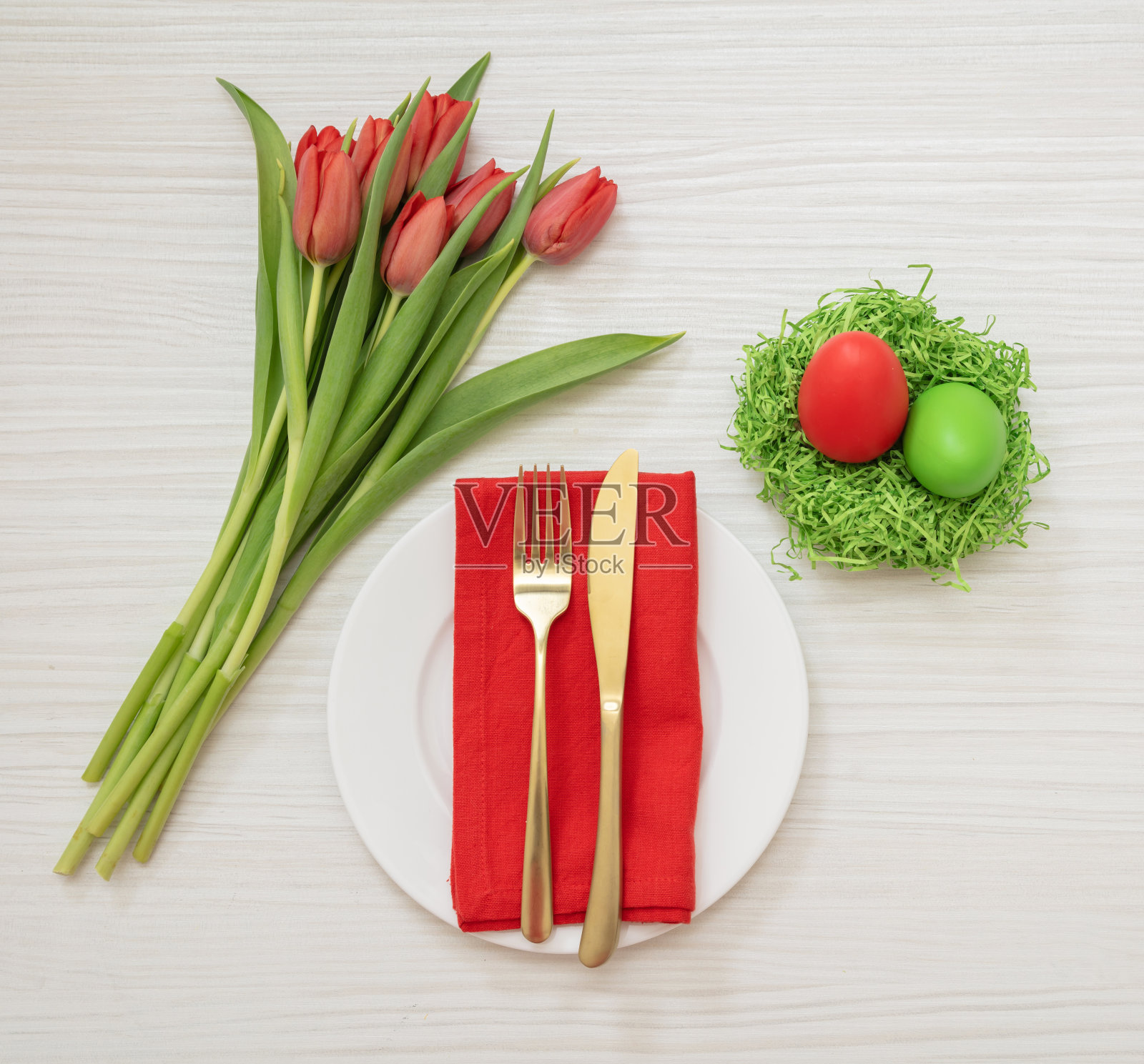 复活节表设置开销。蛋窝和红色郁金香装饰,金色的餐具和盘子。照片摄影图片