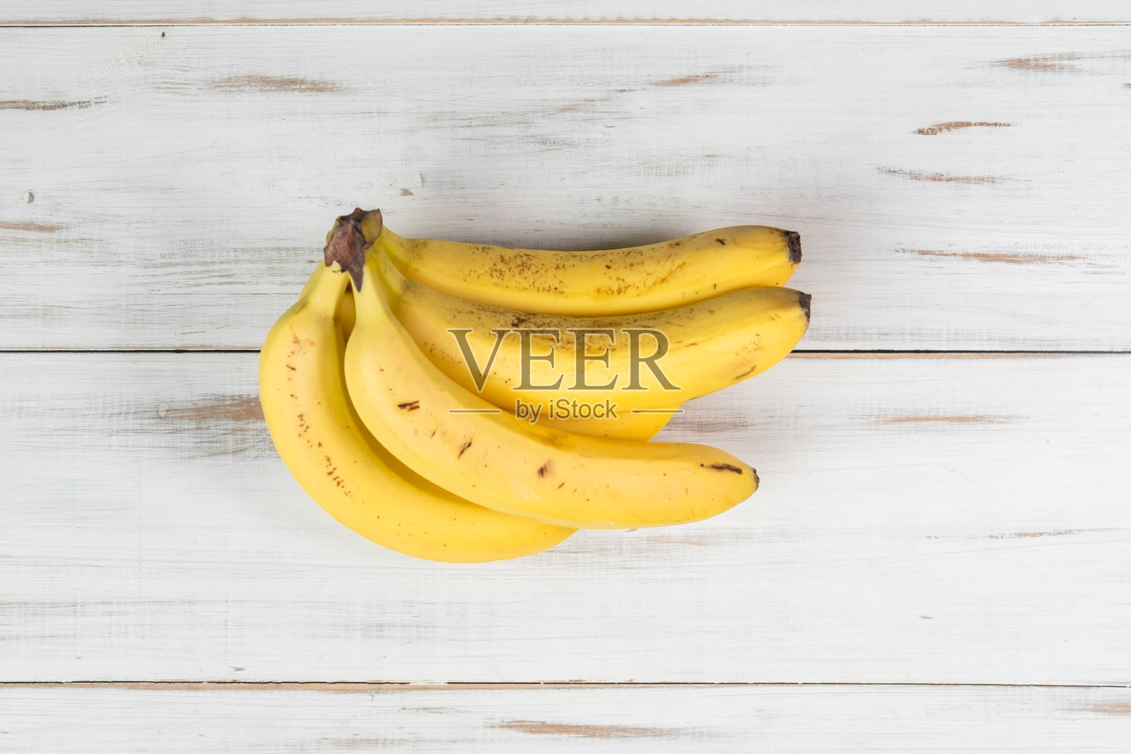 木制背景上的一串香蕉。普通的带斑点的香蕉。照片摄影图片