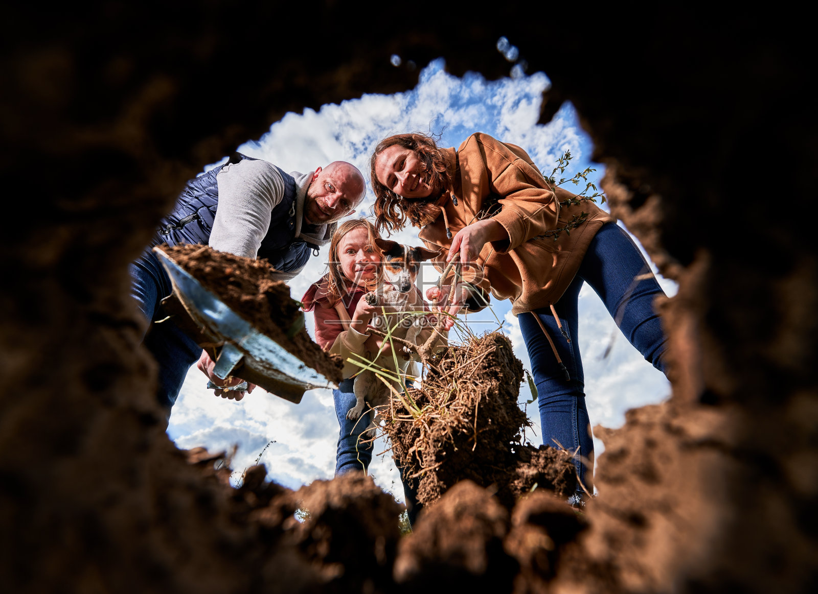 低观笑眯眯的一家人望着洞为植树种苗。照片摄影图片