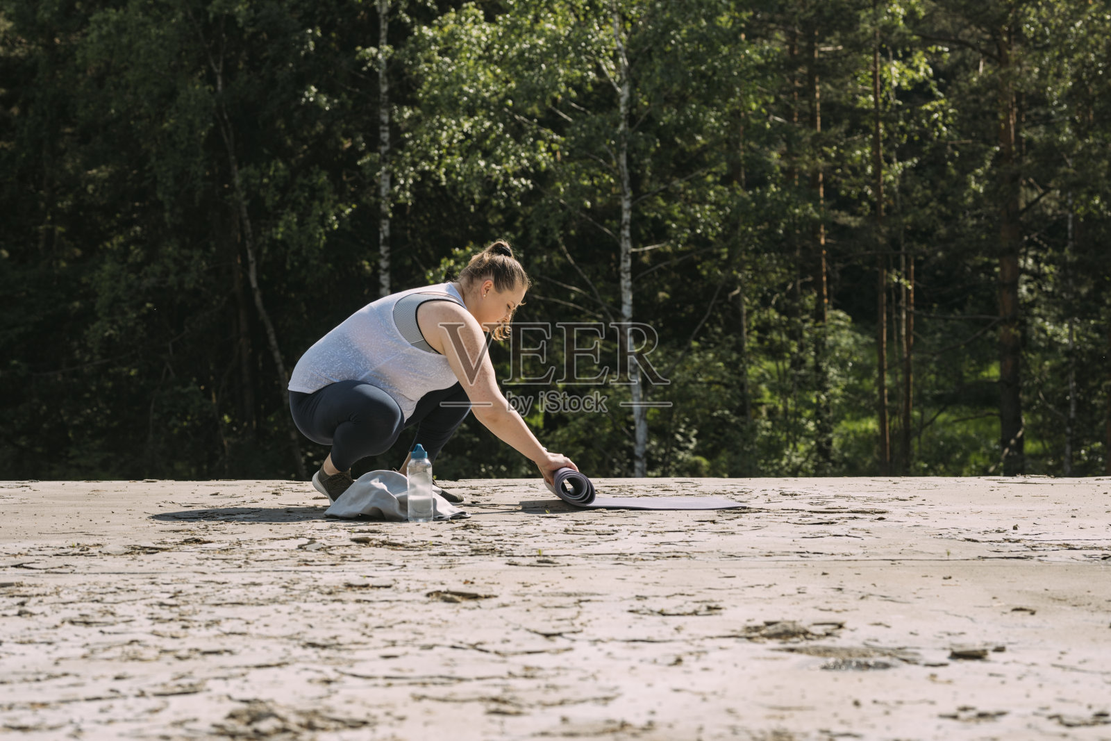 一名白人女性在完成练习后滚动瑜伽垫的侧视图照片摄影图片