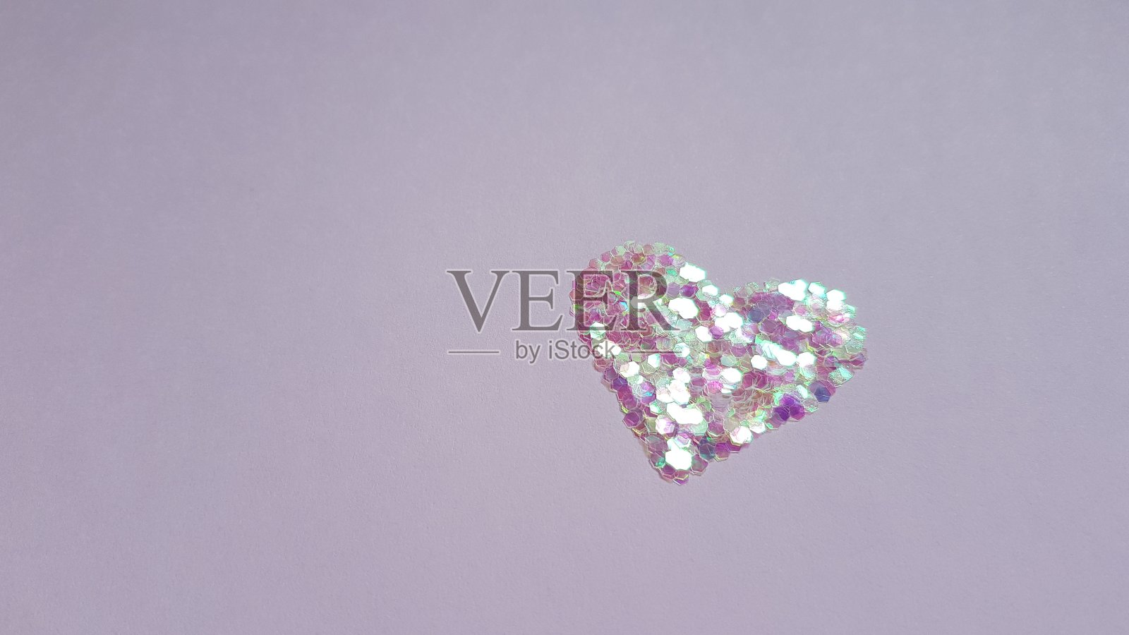 心形的亮片放在紫色的桌子上,复印空间。照片摄影图片