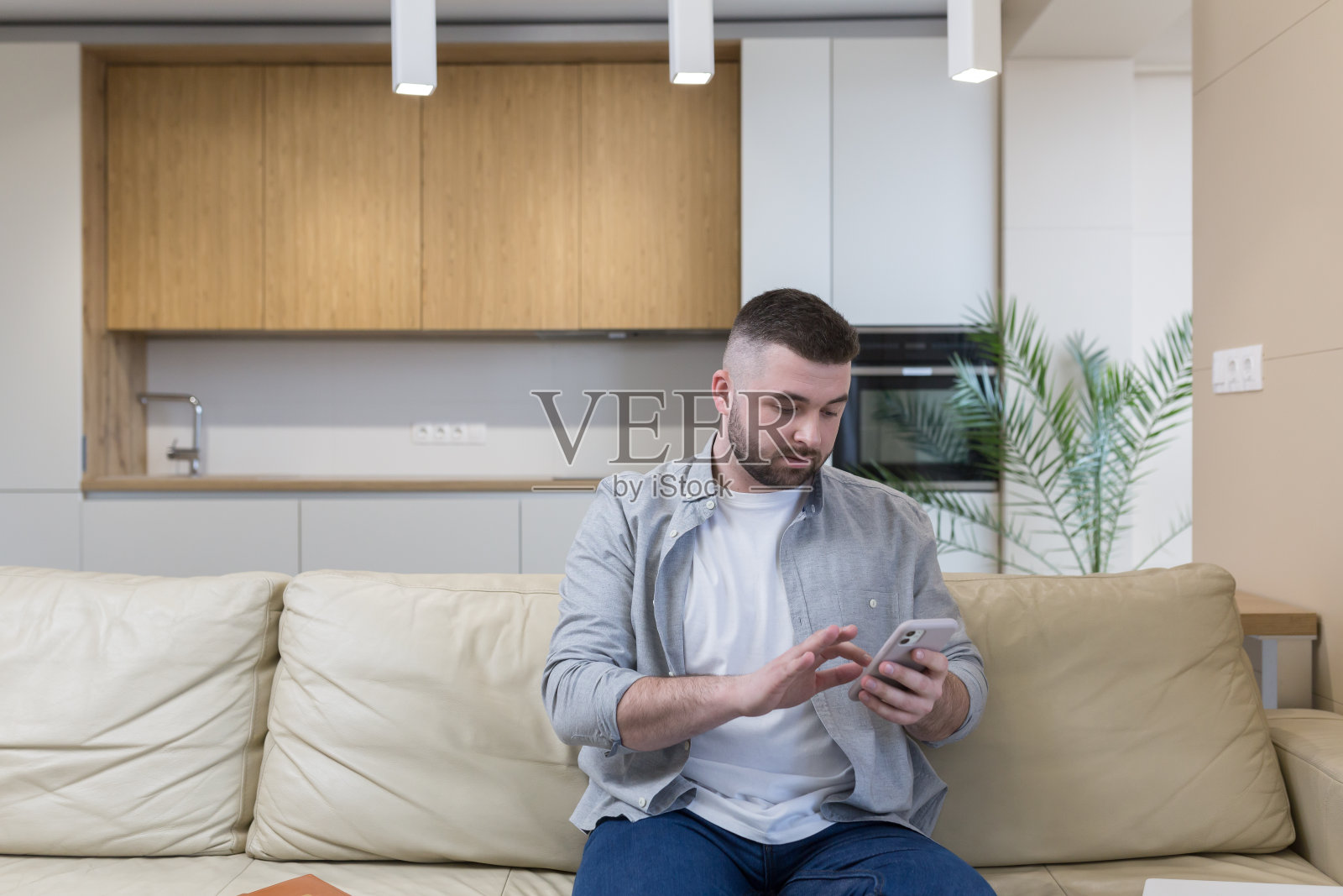 年轻人坐在家里的沙发上,打电话,打电话,视频聊天照片摄影图片