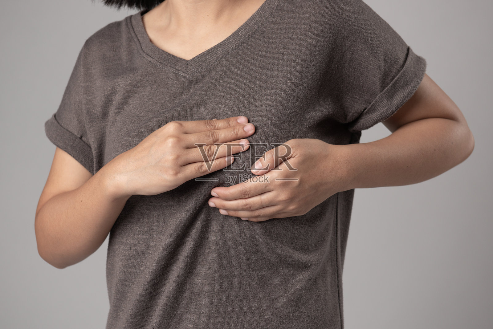 检查她的乳房,妇女的手检查她的乳房肿块在绉纱灰色背景乳腺癌的迹象照片摄影图片