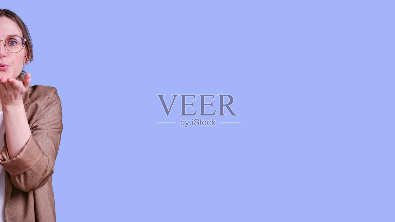 女教师在工作室蓝色的背景上送飞吻,横幅复制空间照片摄影图片