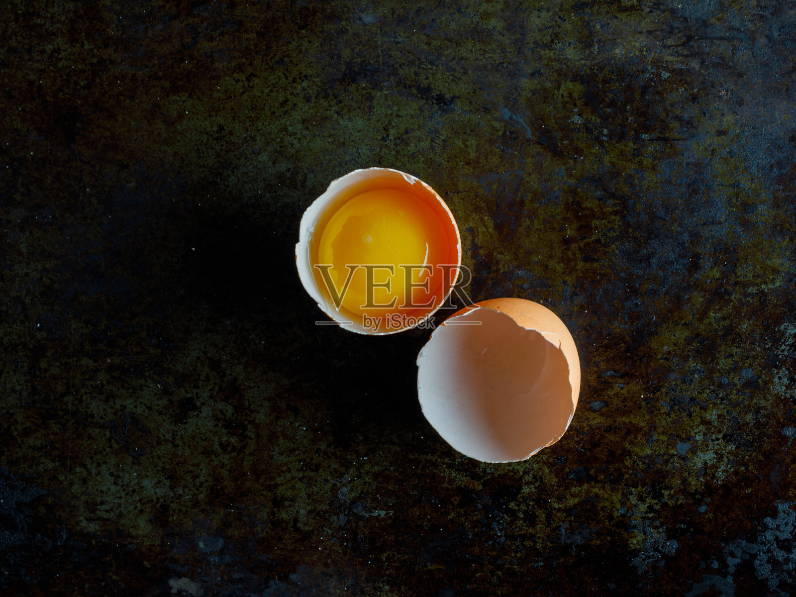 一半的新鲜生破鸡蛋在黑暗的石头背景照片摄影图片