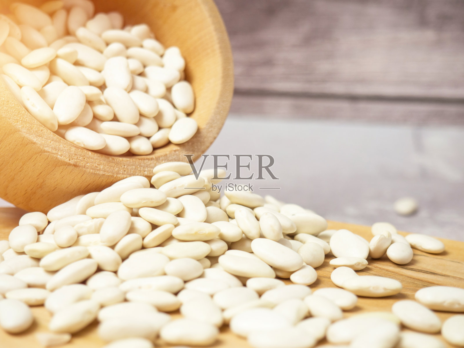 桌上散落着木杯和木勺里的白豆照片摄影图片