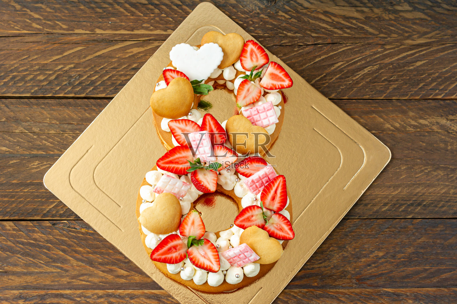 草莓海绵蛋糕,粉色牛奶巧克力棒,银屑,香草奶油和心形8形饼干。国际妇女节春季甜点。甜蜜的礼物照片摄影图片