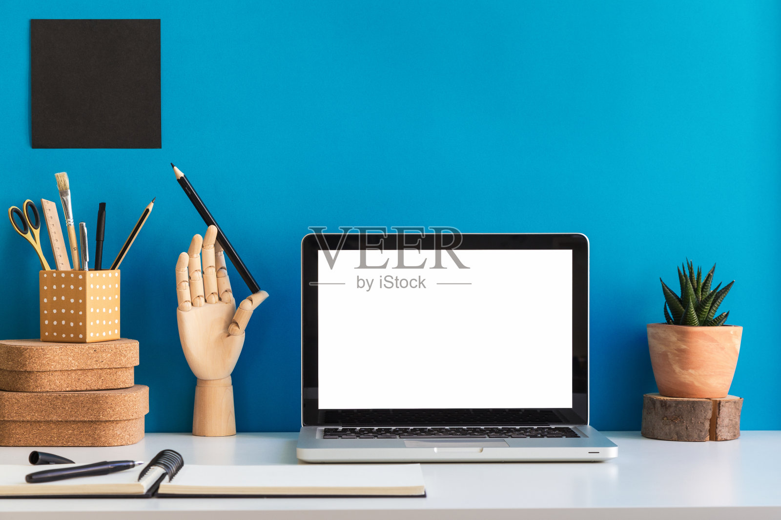 笔记本电脑屏幕在家庭办公室办公桌与用品靠蓝色的墙。照片摄影图片