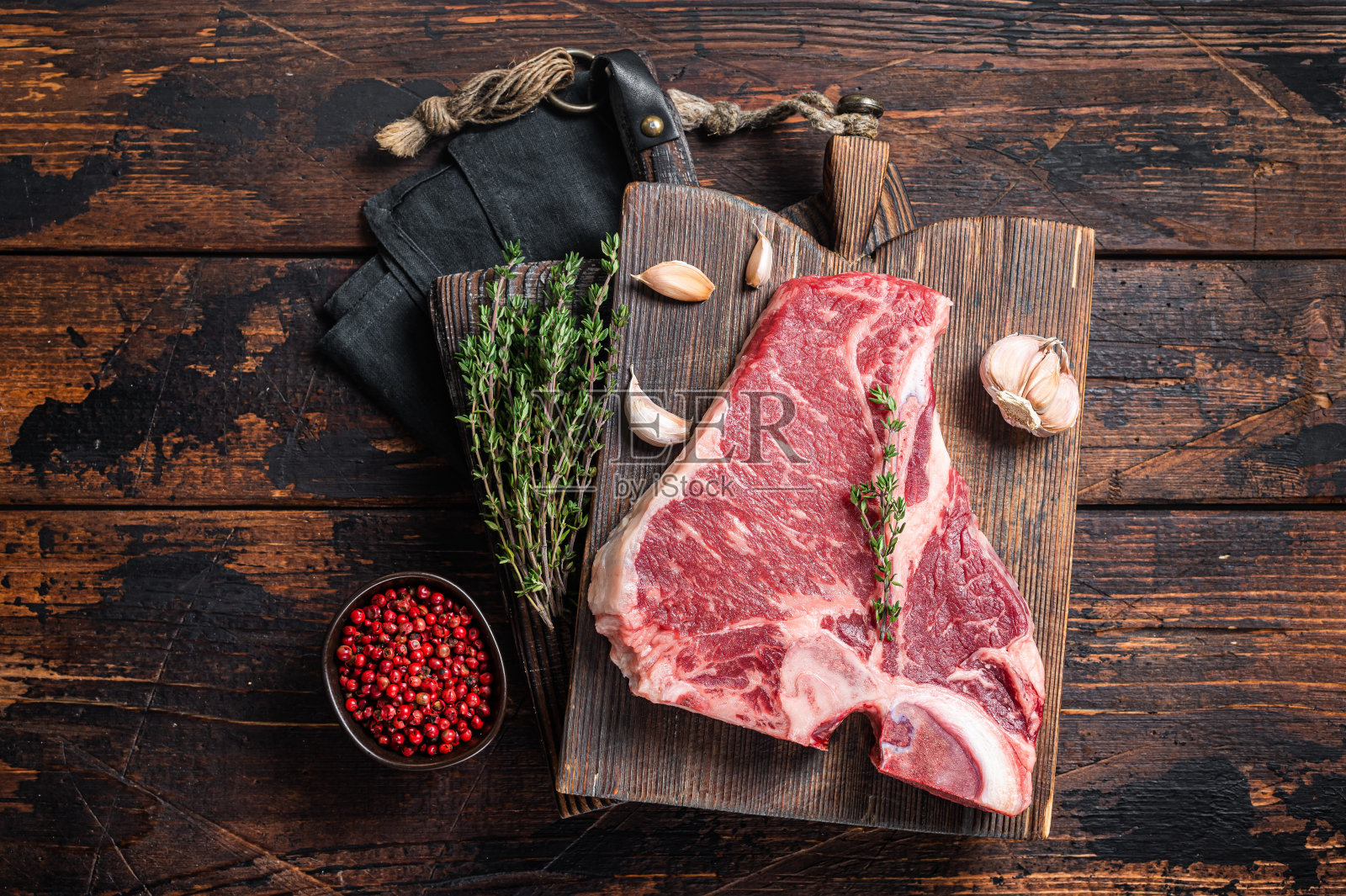 上等t骨牛排,生上等牛排配香草。木制背景。俯视图照片摄影图片